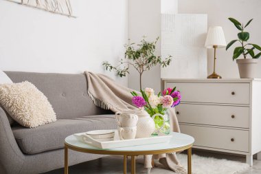 Sümbül çiçekli vazo, çaydanlık ve fincanlar oturma odasındaki sehpanın üzerinde.