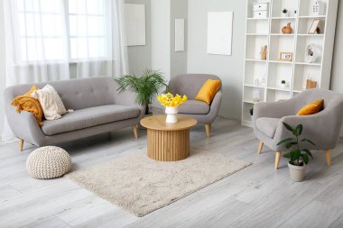 Oturma odasının içinde rahat bir kanepe, koltuklar ve sehpanın üzerinde vazo var.