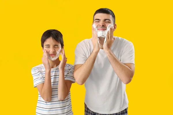 Man His Little Son Applying Shaving Foam Faces Yellow Background — Stok fotoğraf