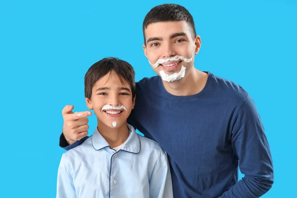かわいいです肖像画の男と彼の小さな息子でシェービング泡で顔に青の背景 — ストック写真
