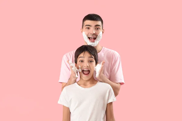 Man His Little Son Applying Shaving Foam Faces Pink Background — Foto de Stock