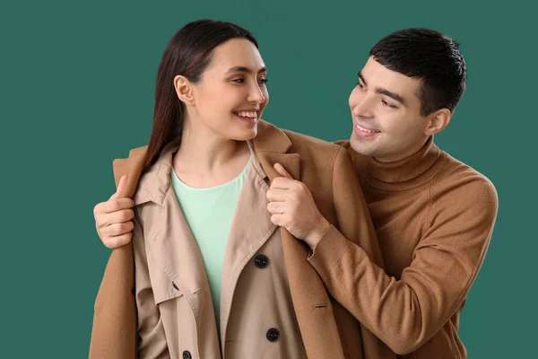 Young Man Putting Coat His Girlfriend Green Background — Stock Photo, Image