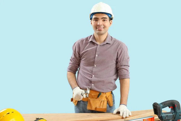 Young Carpenter Hammer Wooden Planks Table Blue Background — Stock Photo, Image