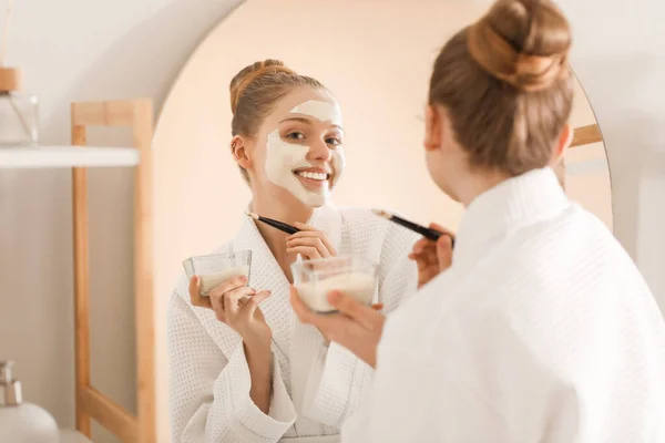 Wanita Muda Menerapkan Masker Kunyit Dengan Kuas Dekat Cermin Kamar — Stok Foto