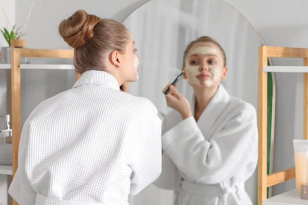 Mujer Joven Aplicando Máscara Cúrcuma Con Cepillo Cerca Del Espejo — Foto de Stock