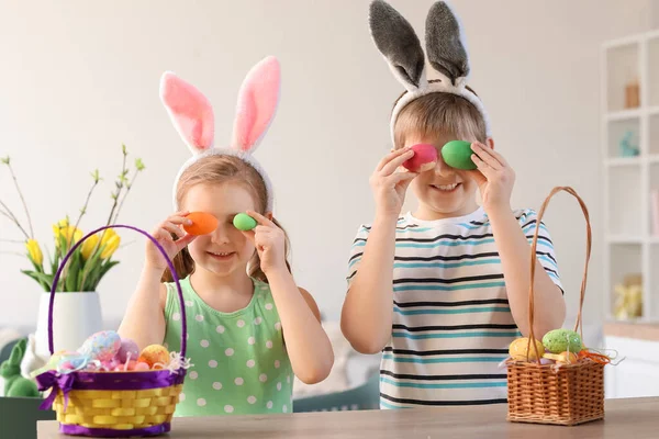 ウサギの耳とキッチンでイースターエッグを持つ面白い小さな子供 — ストック写真