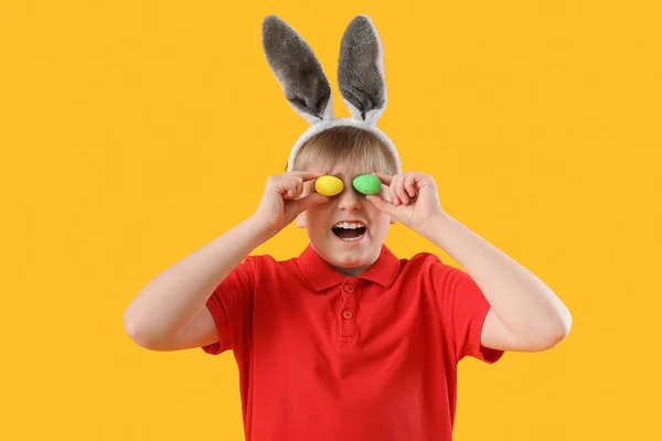 面白い男の子でウサギ耳とともにイースターエッグ上の黄色の背景 — ストック写真
