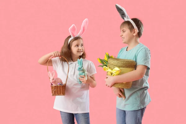 ピンクの背景にイースターエッグとチューリップを持つウサギの耳の中の小さな子供 — ストック写真
