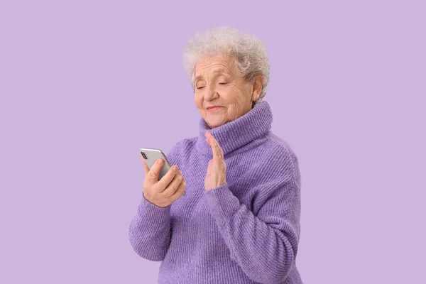 Starsza Kobieta Wideo Telefonu Komórkowego Czacie Tle Liliowym — Zdjęcie stockowe