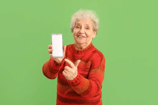 Старшая Женщина Указывает Мобильный Телефон Зеленом Фоне — стоковое фото