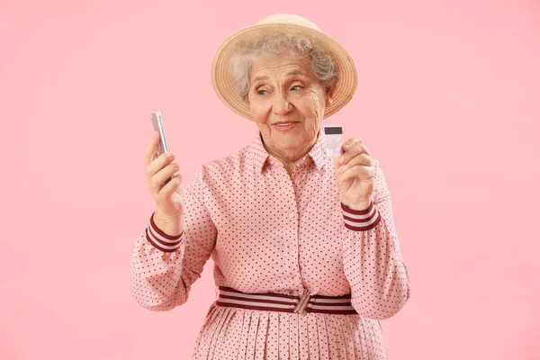 拥有粉色背景的手机和信用卡的老年妇女 — 图库照片