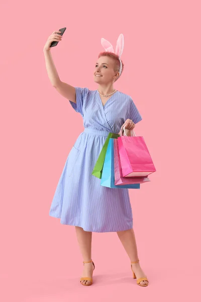 Junge Frau Mit Hasenohren Und Einkaufstaschen Macht Selfie Auf Rosa — Stockfoto