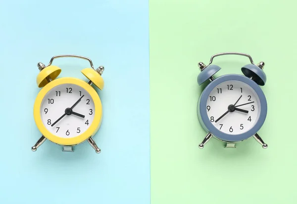 Two alarm clocks on color background
