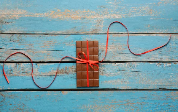 Lezzetli Çikolata Ahşap Arka Planda Kırmızı Kurdeleyle Bağlanmış — Stok fotoğraf