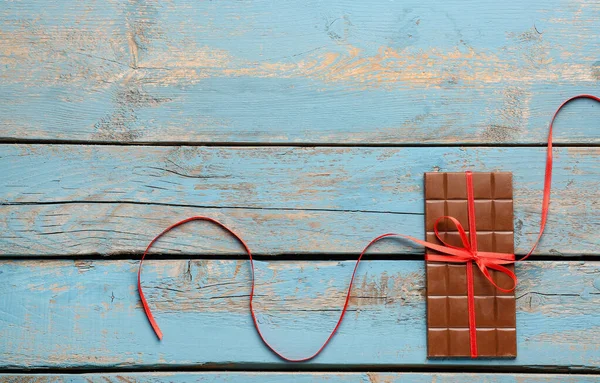 Sabrosa Barra Chocolate Atada Con Cinta Roja Sobre Fondo Madera —  Fotos de Stock