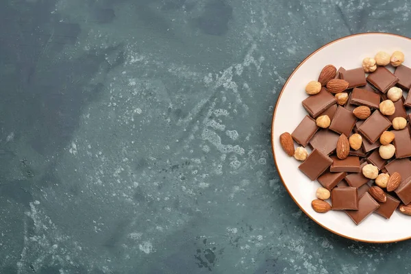 Teller Mit Leckeren Schokoladenstücken Und Nüssen Auf Blauem Hintergrund — Stockfoto