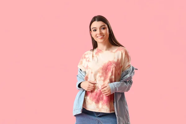 Stylish young woman in tie-dye t-shirt on pink background