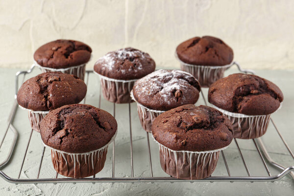 Grid with tasty chocolate cupcakes on table