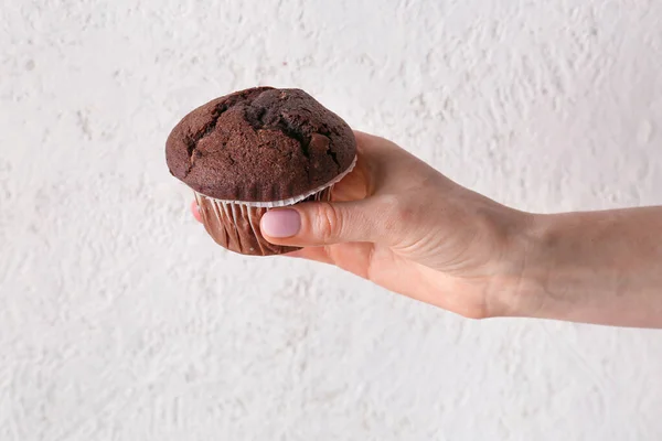 stock image Woman holding tasty chocolate cupcake on light background