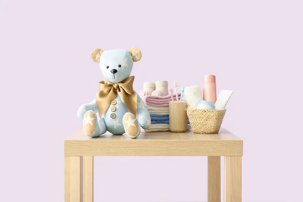 Іграшковий Ведмідь Дитячим Одягом Аксесуарами Столі Біля Бузкової Стіни — стокове фото
