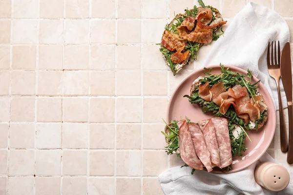 stock image Tasty bacon, jamon and ham bruschettas with arugula on tile background