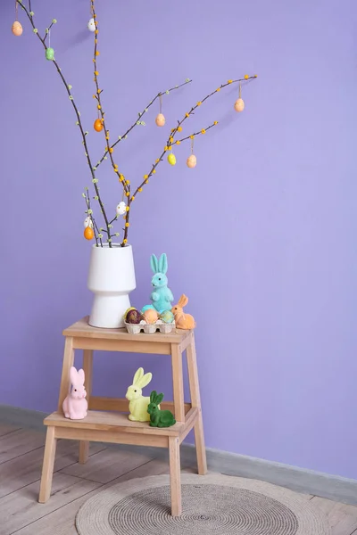 Wazon Gałęziami Drzew Pisanki Króliki Zabawki Drabinie Pobliżu Ściany Liliowej — Zdjęcie stockowe