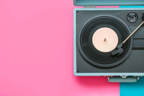 Record player with vinyl disk on color background