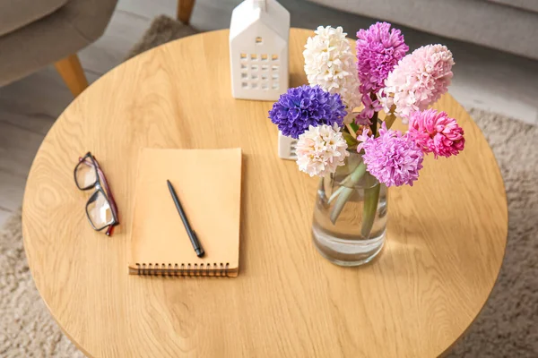 美しいヒヤシンスの花と花瓶 コーヒーテーブルの上の眼鏡やノートブック クローズアップ — ストック写真