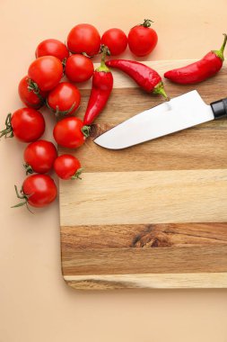 Ahşap kesim tahtası, domates, kırmızı biber ve arka planda bıçak, yakın plan.