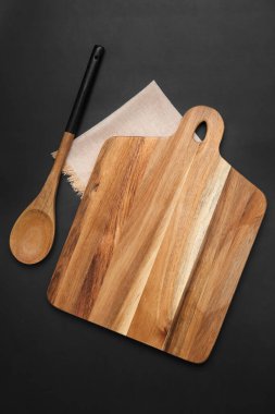 Koyu arkaplanda tahta kesme tahtası ve kaşık.