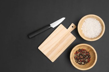 Tahta kesme tahtası, arka planda baharat kaseleri ve bıçak.