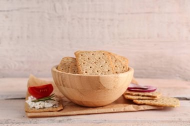 Beyaz ahşap masada lezzetli krakerlerle dolu bir kase