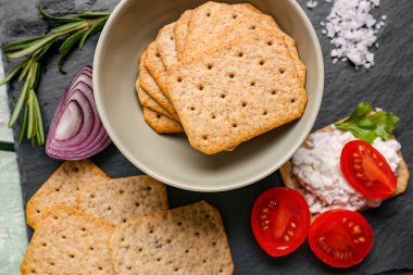 Lezzetli krakerler, krem peynir ve yeşil ahşap arka planda domatesler.