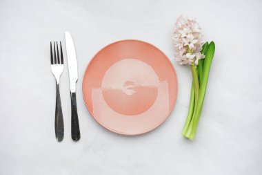 Temiz tabak, çatal bıçak takımı ve beyaz arka planda güzel sümbül çiçeği.