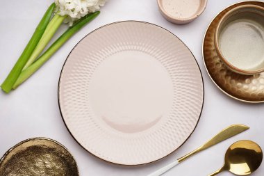 Temiz tabaklar, çatal bıçak takımı ve beyaz arka planda güzel bir sümbül çiçeği kompozisyonu.