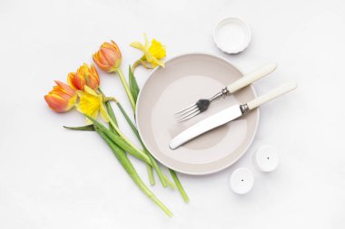 Beyaz zemin üzerinde temiz tabak, çanak çömlek ve güzel çiçekler olan kompozisyon