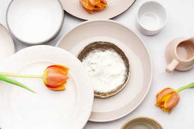 Farklı temiz tabaklar ve beyaz arka planda lale çiçekleri olan kompozisyon