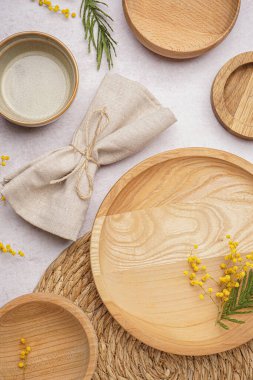 Beyaz grunge masasında temiz ahşap tabaklar, peçete ve mimoza çiçekleri kompozisyonu