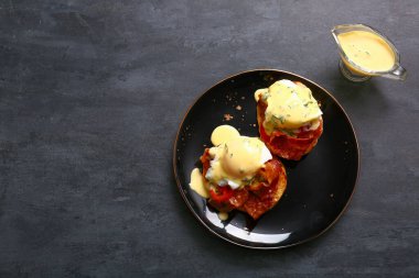 Lezzetli yumurtalı tabak siyah grunge masasında Benedict.