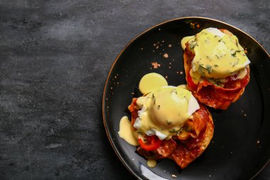 Lezzetli yumurtalı tabak siyah grunge masasında Benedict.