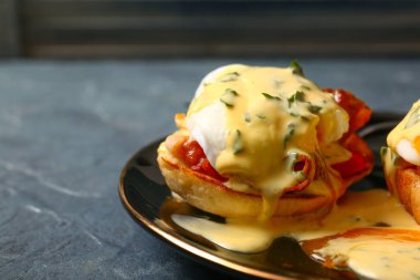 Gri grunge masasında lezzetli yumurtalı Benedict tabağı, yakın plan.