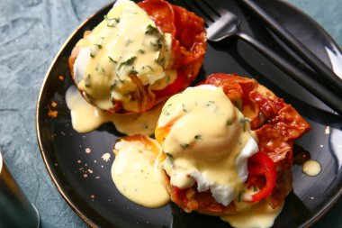 Gri grunge masasında lezzetli yumurtalı Benedict tabağı, yakın plan.