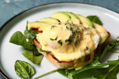 Gri grunge masasında lezzetli yumurtalı Benedict tabağı, yakın plan.