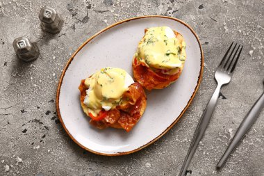Gri grunge masasında lezzetli yumurtalı Benedict tabağı.