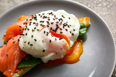 Gri grunge masasında lezzetli yumurtalı Benedict tabağı, yakın plan.