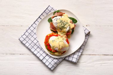 Beyaz ahşap masada lezzetli yumurtalı Benedict tabağı.