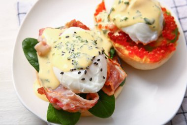 Beyaz ahşap masada nefis yumurtalı Benedict tabağı, yakın plan.