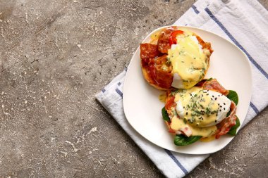 Gri grunge masasında lezzetli yumurtalı Benedict tabağı, yakın plan.