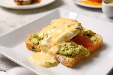 Benedict yumurtalı tabağı beyaz masada, yakın plan.