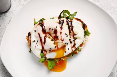 Benedict yumurtalı tabağı beyaz masada, yakın plan.